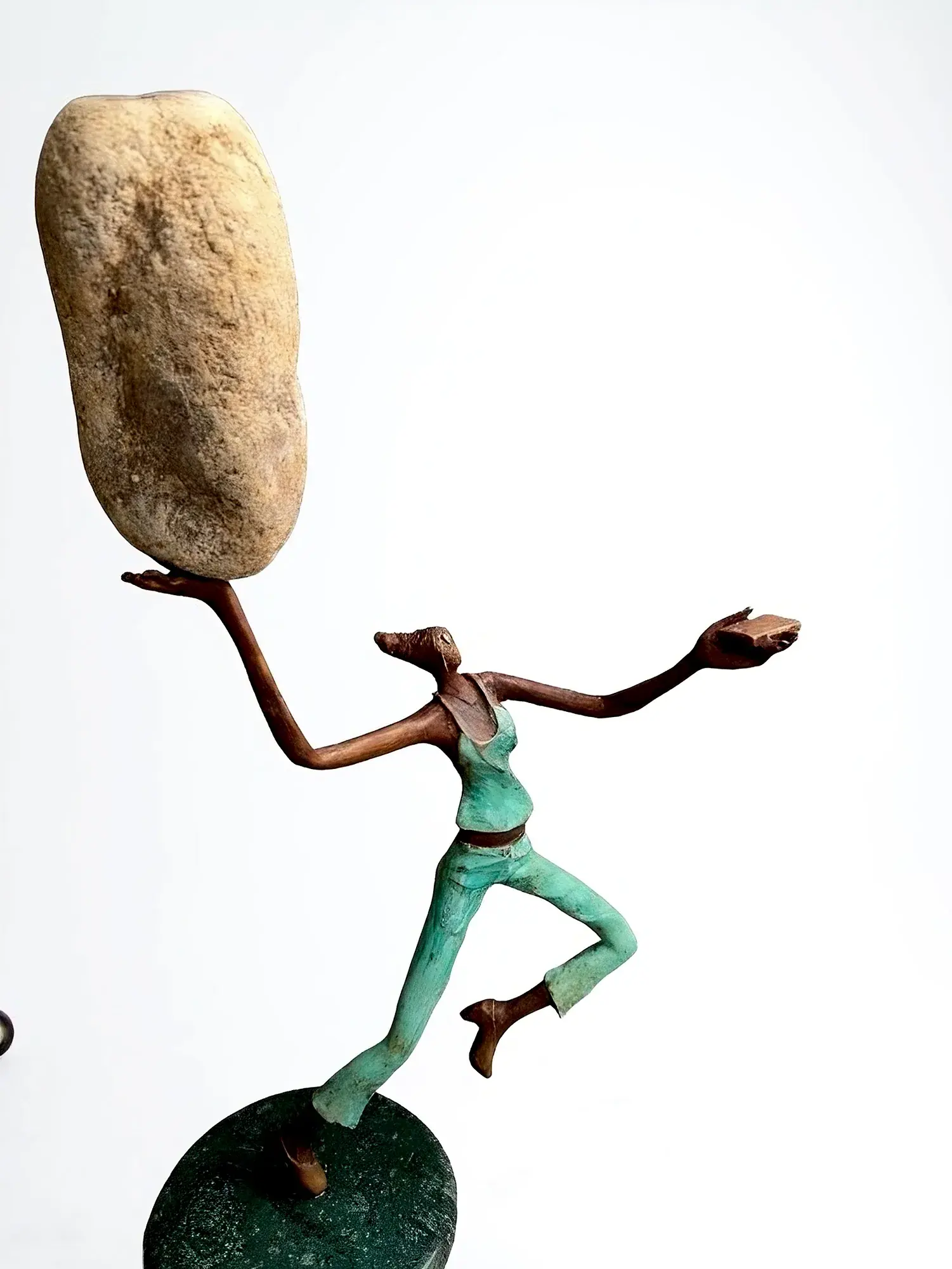 Sanjeevani II — bronze flying figure balancing a stone overhead, mounted on a round green base