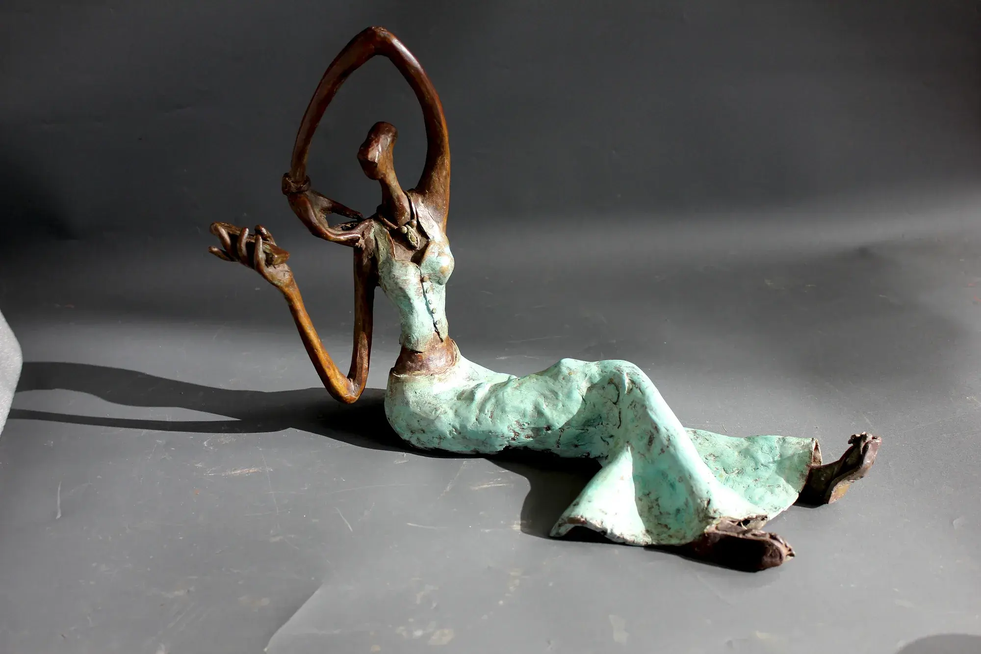 Alasya Kanya VII — bronze figure reclining with one arm extended along the ground in a dramatic diagonal pose
