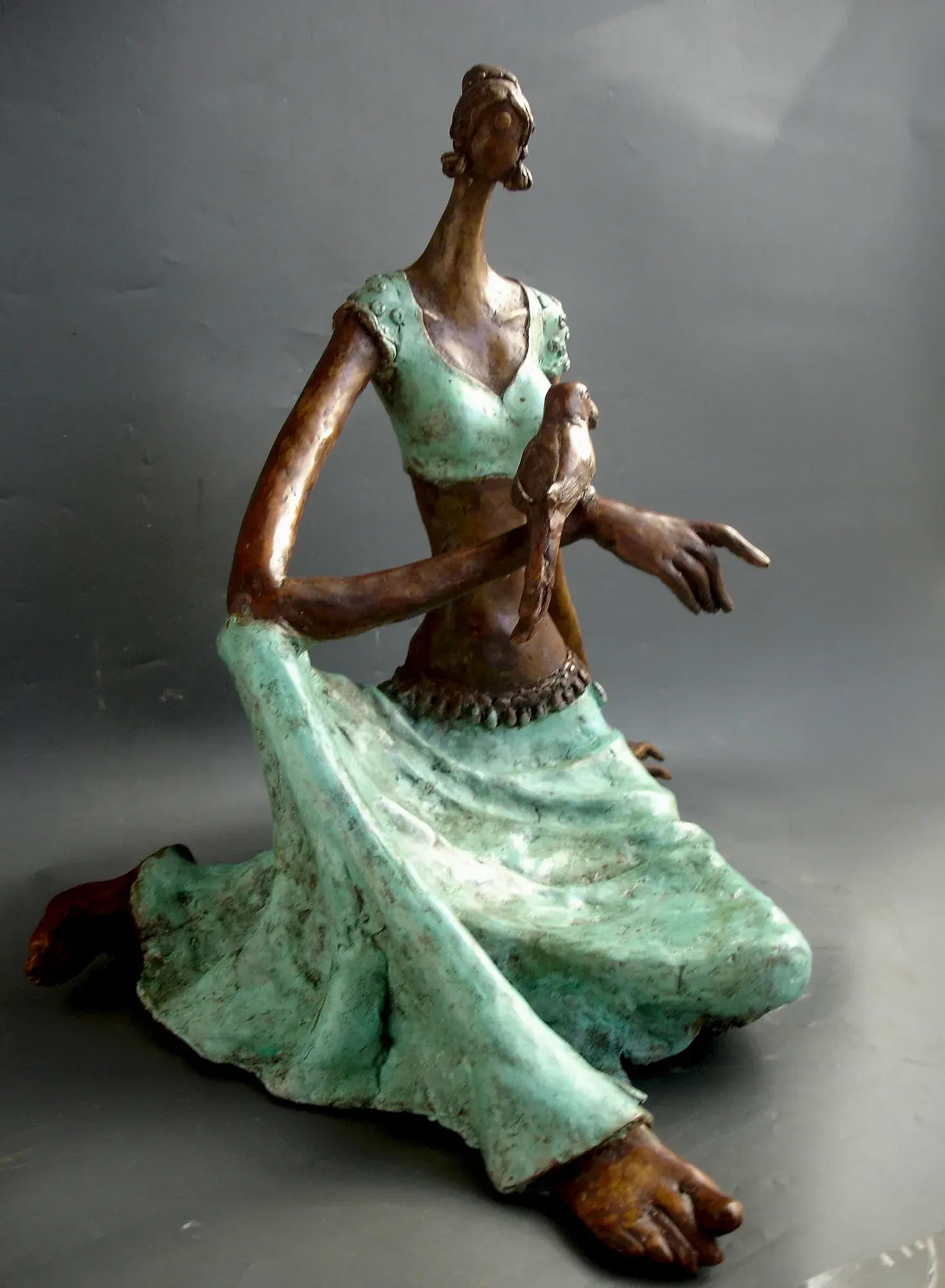 Lady with a Parrot II — bronze seated figure in mint-green patina dress, arm crossed to the chest cradling a parrot