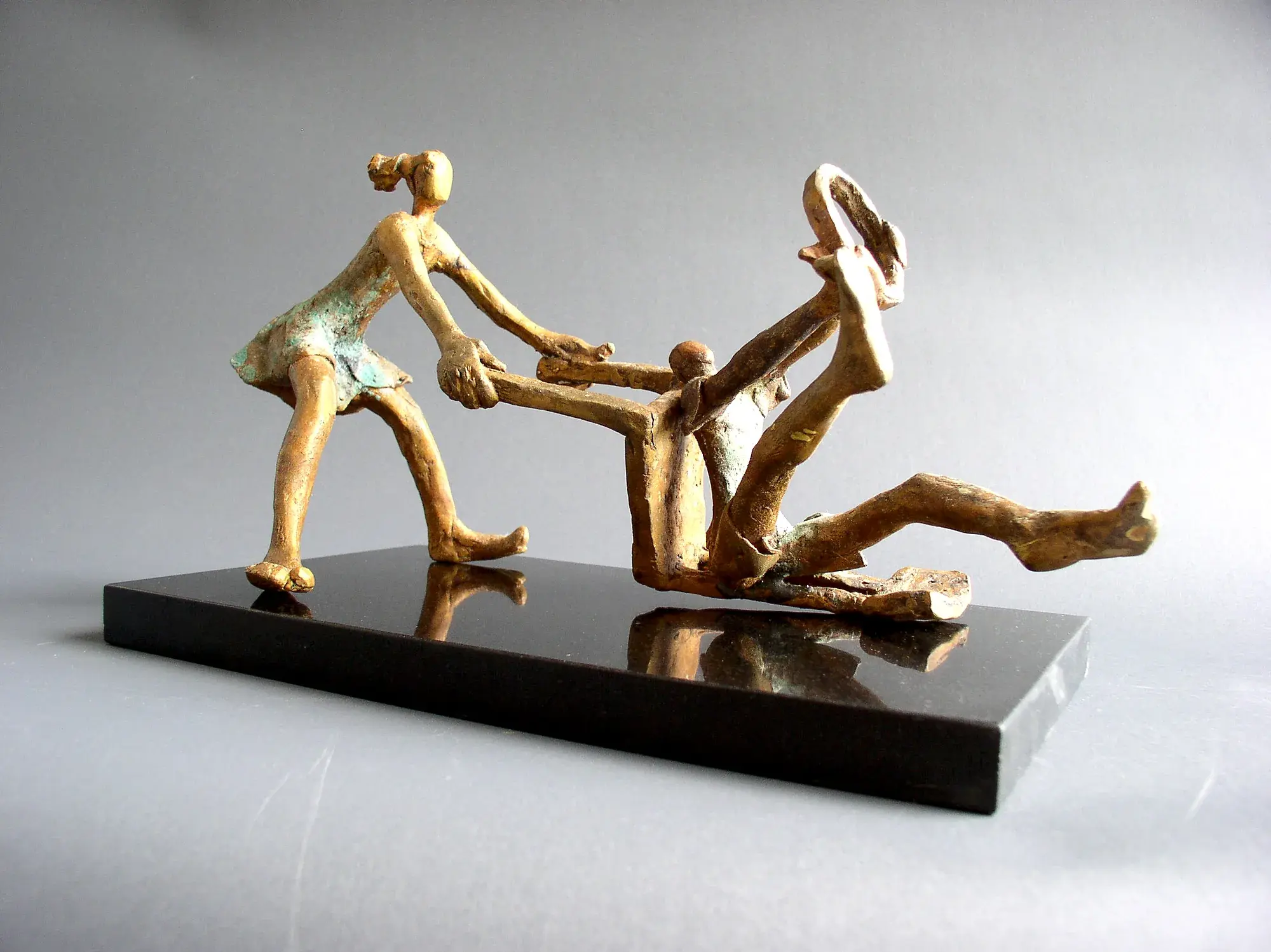 Two bronze children's figures on a playground swing structure, gold-bronze patina