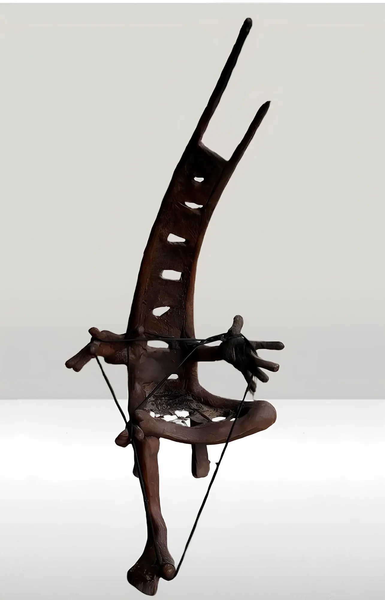 Abstract bronze sculpture, a rib-cage-like curved form with carved hands grasping strings at its base