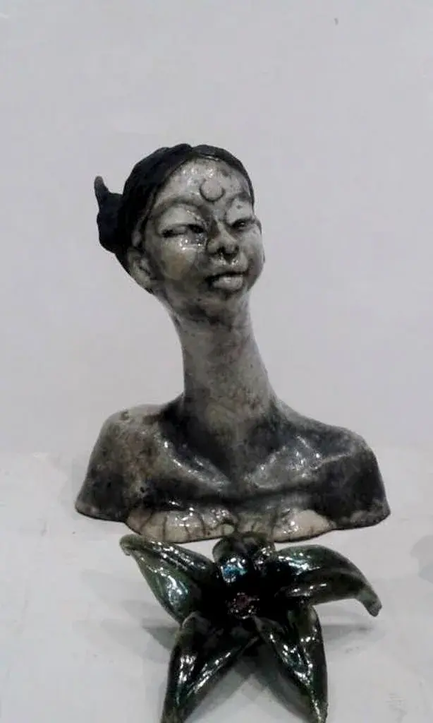 A ceramic bust with a crescent-moon motif on the forehead, mounted on a flower-shaped green base
