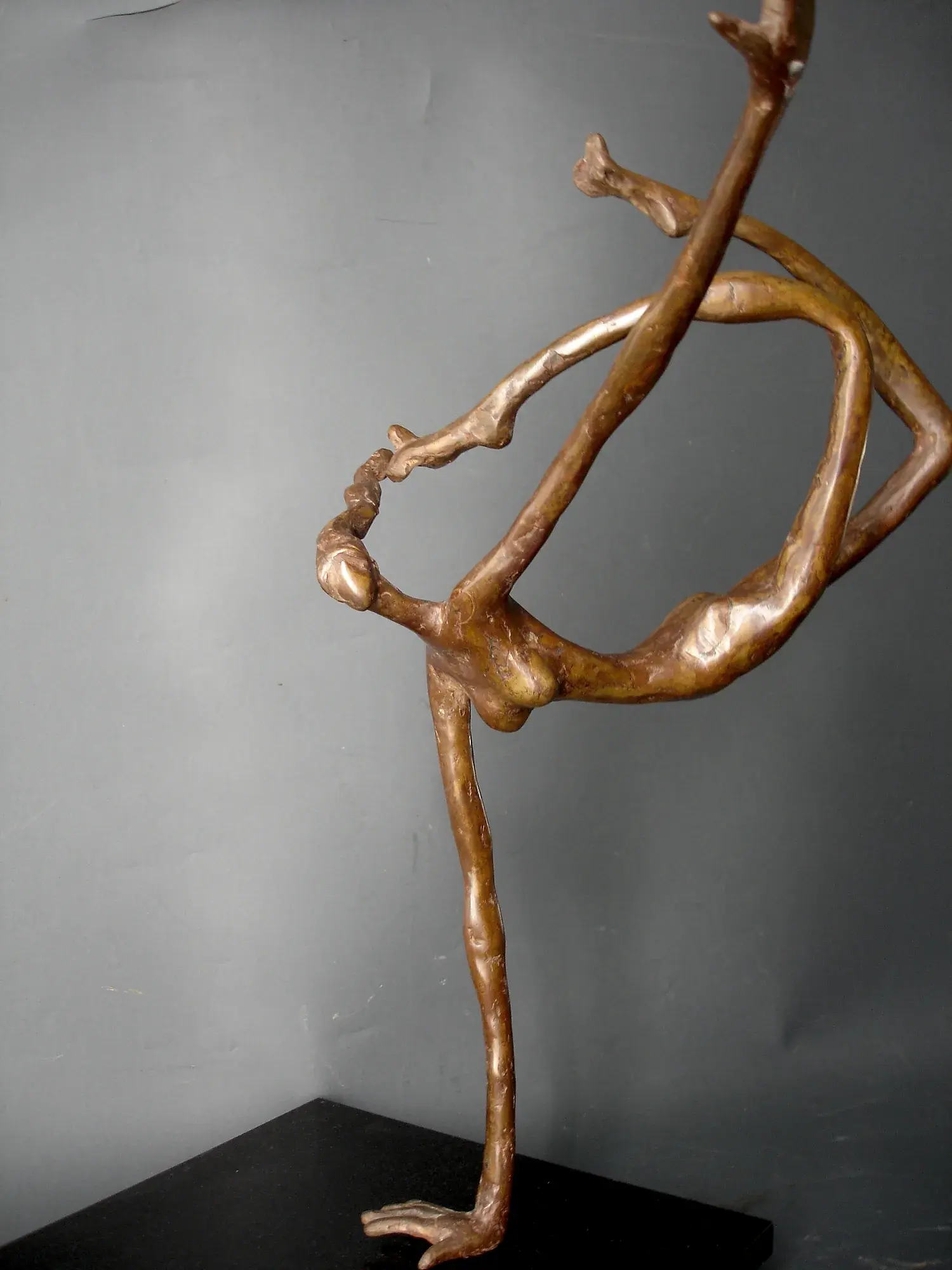Bronze acrobat figure balanced in a one-legged backbend on a black base