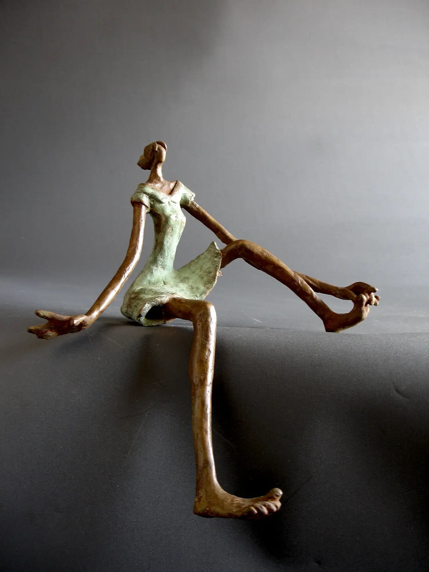 Three small bronze dancing figures joined by flowing ribbon-like forms overhead, on a black base